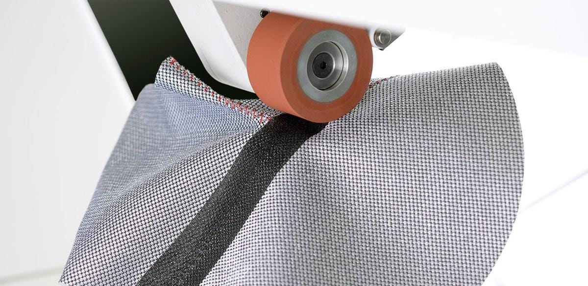 Roller of a PFAFF 8303 heat sealing machine applying tape over a seam